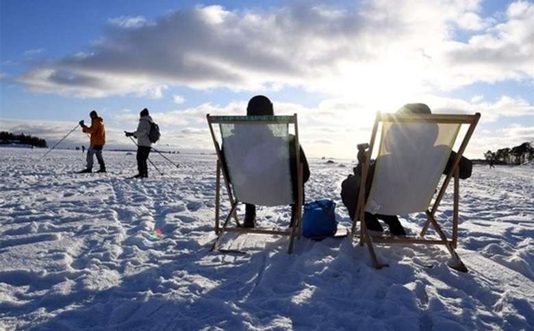 Finnish people enjoy warm sunshine along the river in